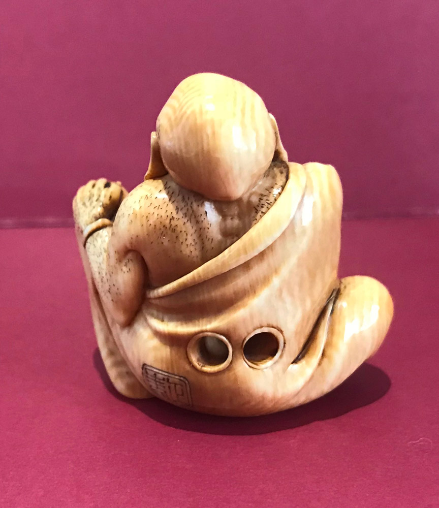 Ivory netsuke of hotei tweezing his nose hair